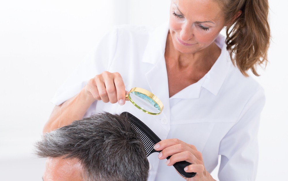 Female Dermatologist Looking At Patient's Hair Through 