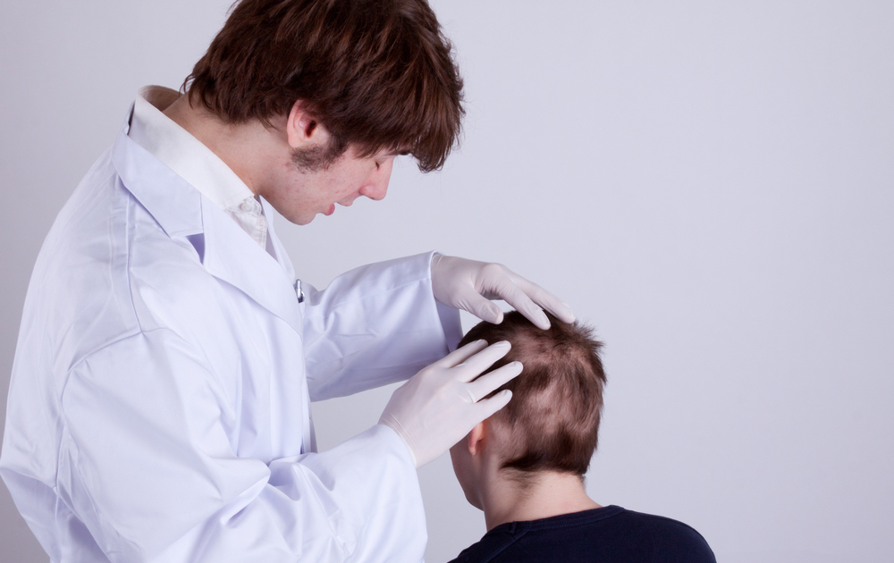 A doctor examines the head of a young man