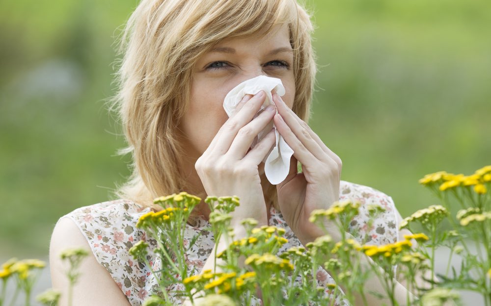 Woman blowing nose into tissue outdoors